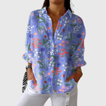 Lichtgewicht damesblouse met kleurrijke print en ruime snit, gedragen op een nette pantalon